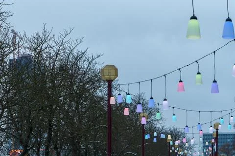 Colorful festive string lights line hanging over city street on winter day,.. Foto stock