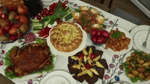 Colorful festive table spread featuring various traditional dishes, fruits, and Vídeo Stock 332736947