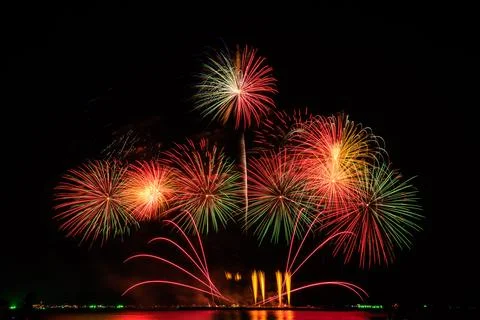 Colorful Firework Bursts Exploding Over Dark Reflective Water Night Shot Stock-Fotos