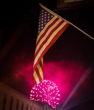 Colorful firework exploding under an American flag at night Foto stock