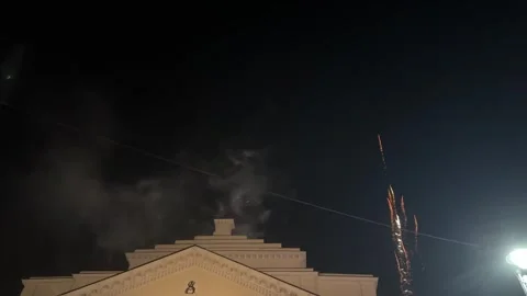 Colorful fireworks explode in the night sky above a historic building Stock Footage 313908914