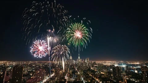 Colorful fireworks explode in the night sky above the city. The camera slowly Stock Footage 318214272
