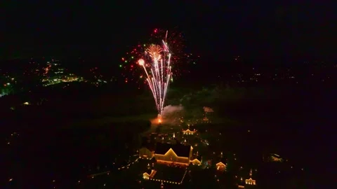 Colorful fireworks explode in the night sky over a city. Bright lights shine Stock Footage 332988578