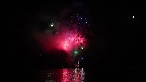 Colorful fireworks exploding in the night sky with reflections on the water, 스톡 동영상 343275338