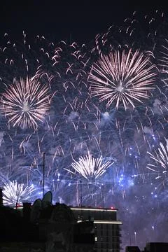 Colorful fireworks exploding over city buildings at night Stock Photos