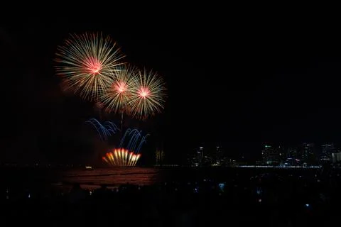 Colorful Fireworks Exploding Over Coastal City Skyline At Night Wide Shot Stock Photos