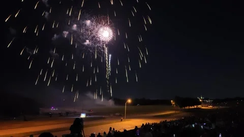 Colorful fireworks exploding over a crowd at night Stock Footage 340938875
