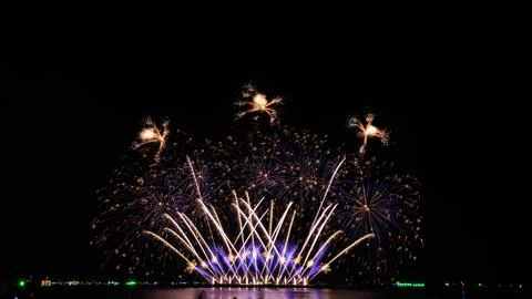 Colorful Fireworks Exploding Over Ocean Water With Reflections At Night 스톡 사진