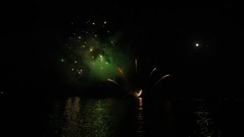Colorful fireworks exploding over water at night, illuminating boats and 스톡 동영상 343280226