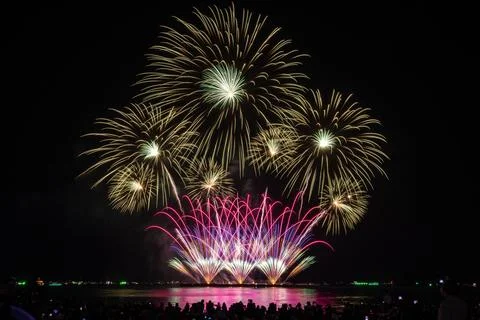 Colorful Fireworks Exploding Over Water During Night Festival Wide Shot Foto stock
