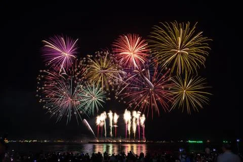 Colorful Fireworks Exploding Over Waterfront Reflecting Vibrant Light Wide Sh Foto stock