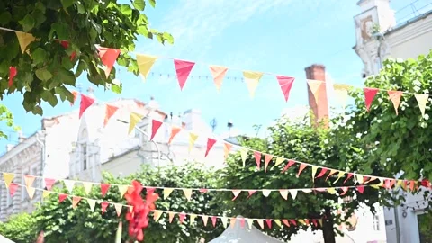Colorful flags hang between trees in a vibrant outdoor space with a clear blue Stockbeeldmateriaal 337101216