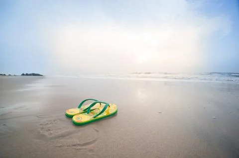 Colorful flip flops lying on beach in pondicherry with waves sur Stock Photos