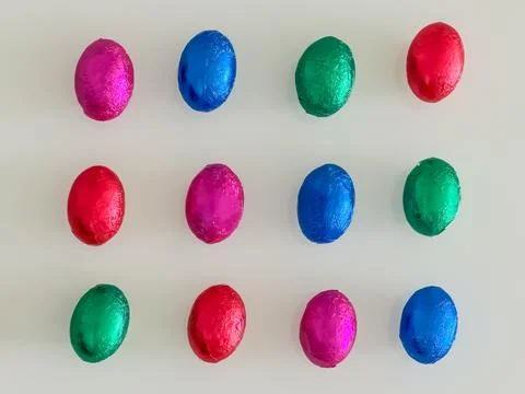 Colorful Foil-Wrapped Easter Eggs Arranged in Grid Top View Stock Photos