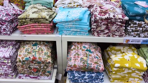 Colorful folded cotton kurta stack display in retail store with floral prints Stock Footage 334491555