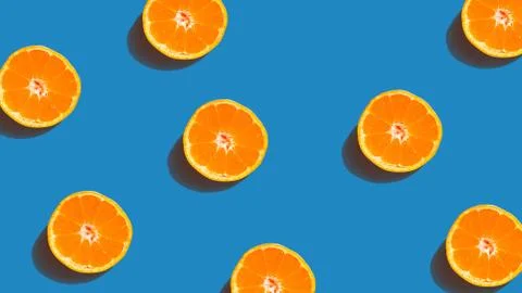 Colorful fruit pattern of fresh orange slices on blue background. From top vi Stock Photos