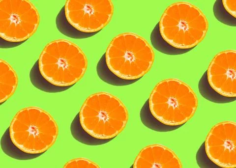 Colorful fruit pattern of fresh orange slices on green background. From top v Stock Photos