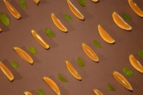 Colorful fruit pattern of fresh orange slices on brown background with leaves Stock Photos