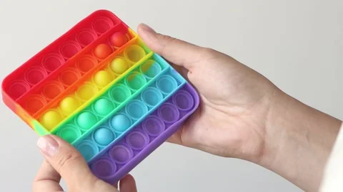 Colorful game in female hands on a solid background. Antistress toy close-up. Stock Footage 155460153