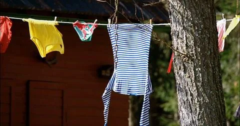 Colorful Garments Flutter In Breeze, Rustic Setting With Vibrant Baby Outfits Stock Photos