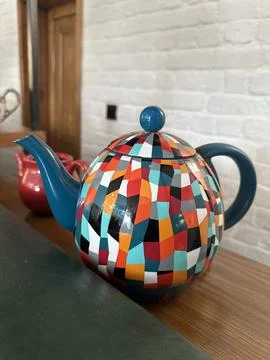Colorful Geometric Pattern Teapot with Teal Handle and Spout on Wooden T 库存照片