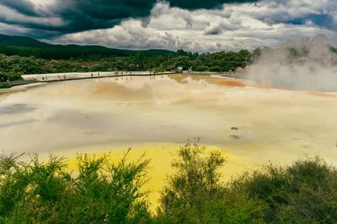 Colorful Geothermal Pool Under Dramatic Storm Clouds Photos