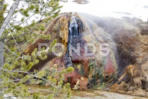 Colorful geyser with steam on riverfront in Yellowstone National Park in wint Stock Photos
