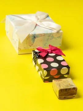 Colorful gift boxes of different sizes are laid out in a row on a bright yell Stock Photos