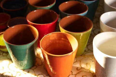 Colorful Glazed Ceramic Cups on Patterned Tablecloth Stock Photos