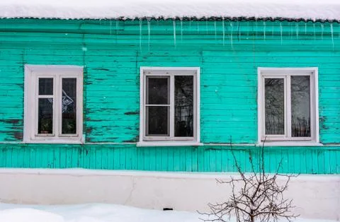 Colorful green small house in the snow with small paint loss Stock Photos
