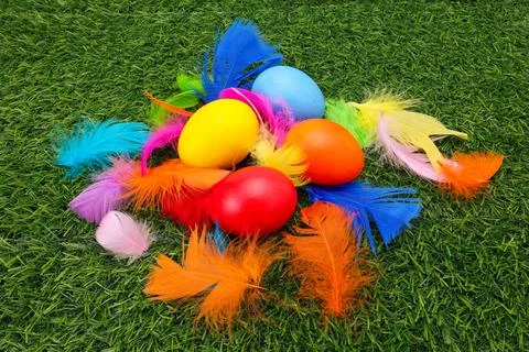 Colorful Hand Painted Easter Eggs with Dyed Feathers on Green Fake Grass Foto stock