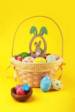 Colorful hand-painted Easter eggs in a wicker basket with a wooden bunny or.. Stock Photos