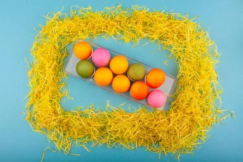 Colorful handmade Easter eggs in a frame made of dry grass. Top view of an open Stock Photos