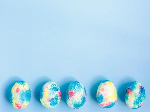 Colorful handmade Easter eggs painted like Earth on blue paper background with Stock Photos