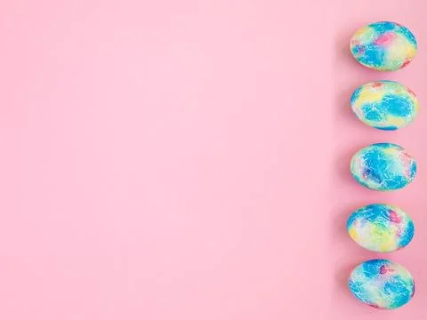 Colorful handmade Easter eggs painted like Earth on pink paper background with Stock Photos