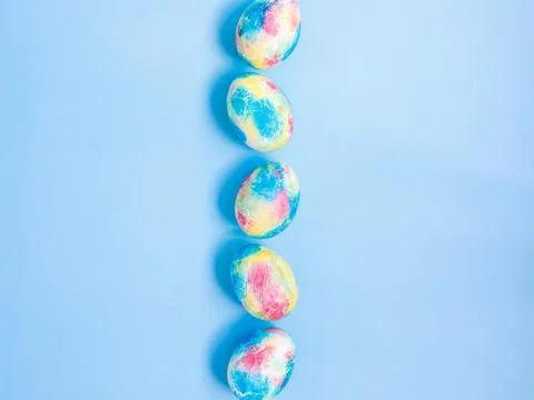 Colorful handmade Easter eggs painted like Earth in row on blue paper background Stock Photos