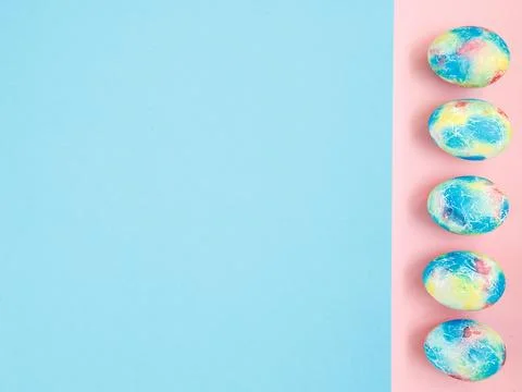 Colorful handmade Easter eggs painted like Earth on blue pink paper background Stock Photos