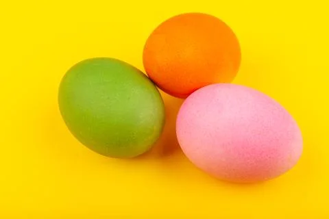 Colorful handmade Easter eggs. Top view of three eggs. Isolated on a yellow Stock Photos