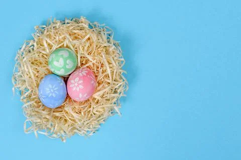 Colorful handmade painted Easter eggs in the nest isolated on a blue backgrou Stock Photos