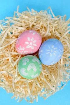Colorful handmade painted Easter eggs in the nest on a blue background. Easter Stock Photos