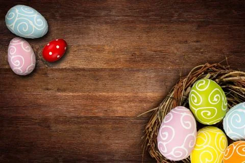Colorful happy easter eggs in bird nest and tulips on dark empty rustic old o Stock Photos