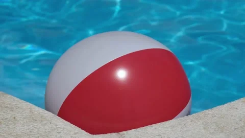 Colorful inflatable beach ball floating in shiny blue swimming pool near edge Video stock 199889412