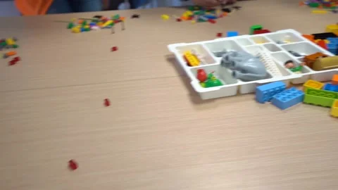 Colorful interlocking plastic brick piles and white game box on table by Stock Footage 131219264