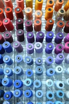 Colorful knitted thread spools put on a shelf at a shop Stock Photos