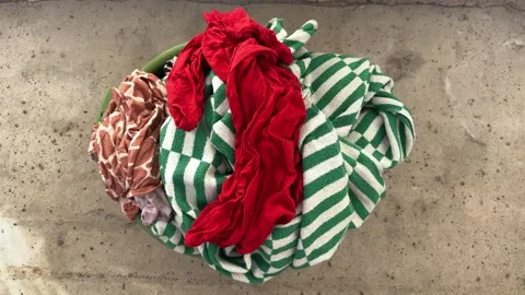 Colorful laundry basket with red clothes and green striped towels  Vídeo Stock 343407601