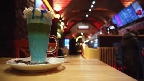 Colorful layered beverage served in clear glass mug with whipped cream topping Stock Footage 335762602