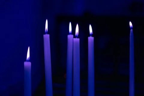 Colorful light candle flame close-up in church for religious ritual. Black Stock Photos