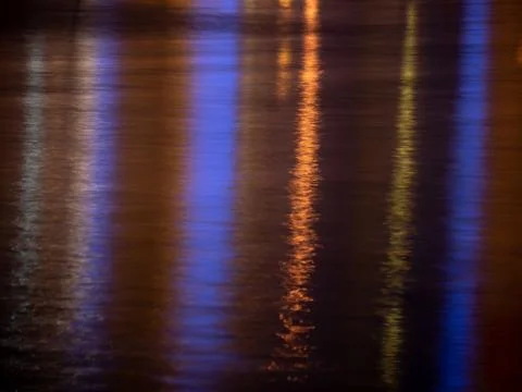 Colorful light reflection on the water surface at night. Stock Photos
