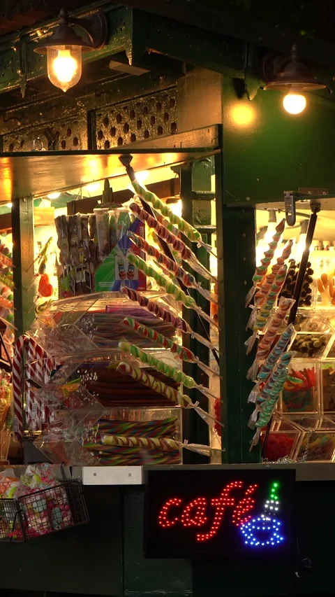Colorful Lollipops and Candy Display at Nighttime Outdoor Cafe Kiosk Stock Footage 334943082