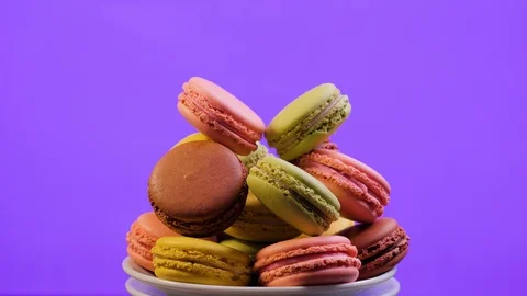 A colorful macaroons are rotating on violet background Stock Footage 106985630